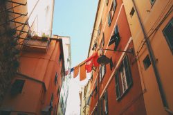 Wet clothes hanging on a line between two residential buildings in an alley in Genoa