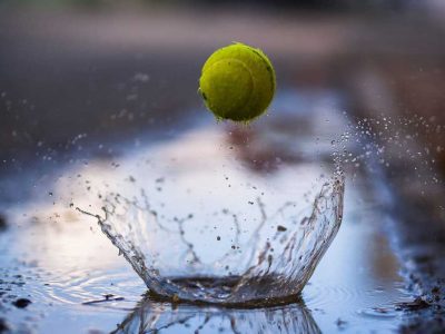 Tennis ball bouncing through a puddle of water.